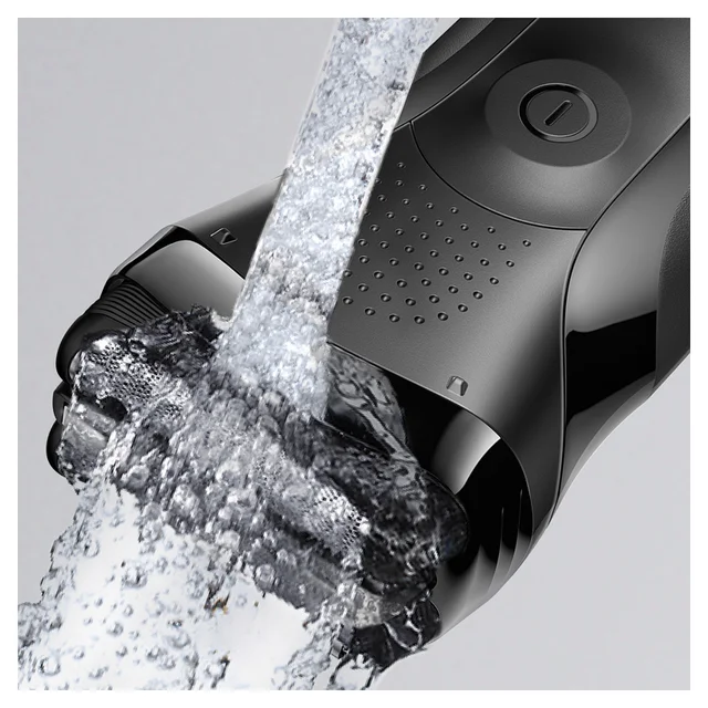 Braun electric shaver being rinsed under water, highlighting its waterproof design.